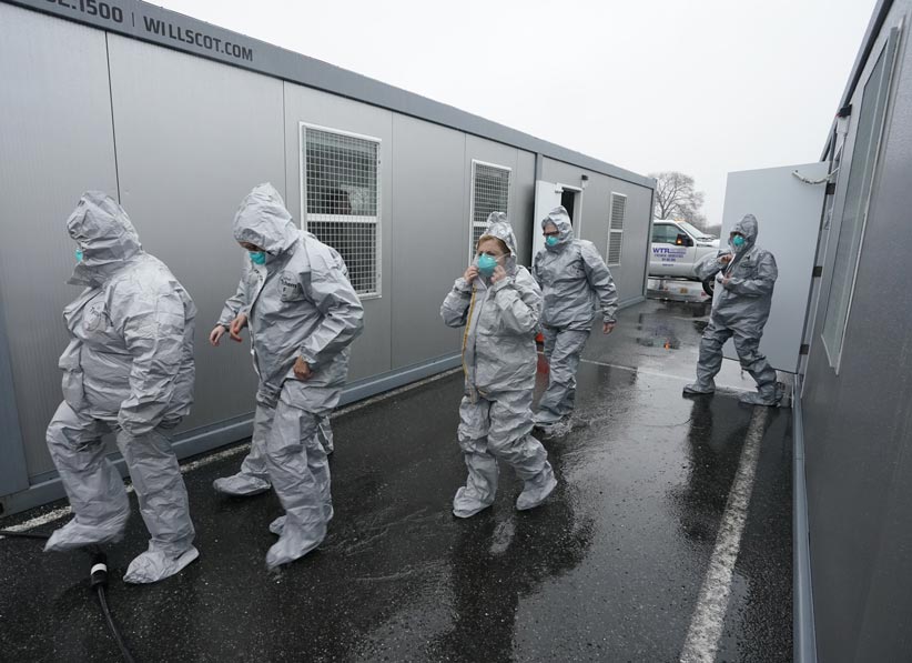 People in protective suits leaving FLEX trailers